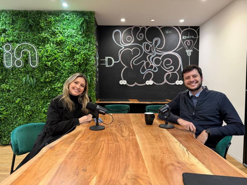 Two founders recording a podcast episode at a wooden table with studio microphones